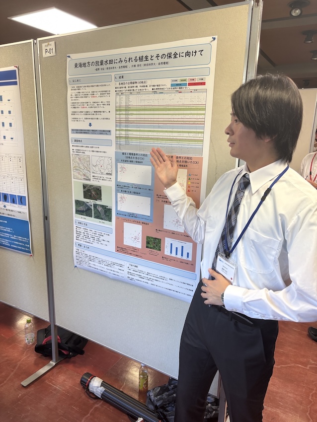 ポスターの前で来場者に説明する学生
