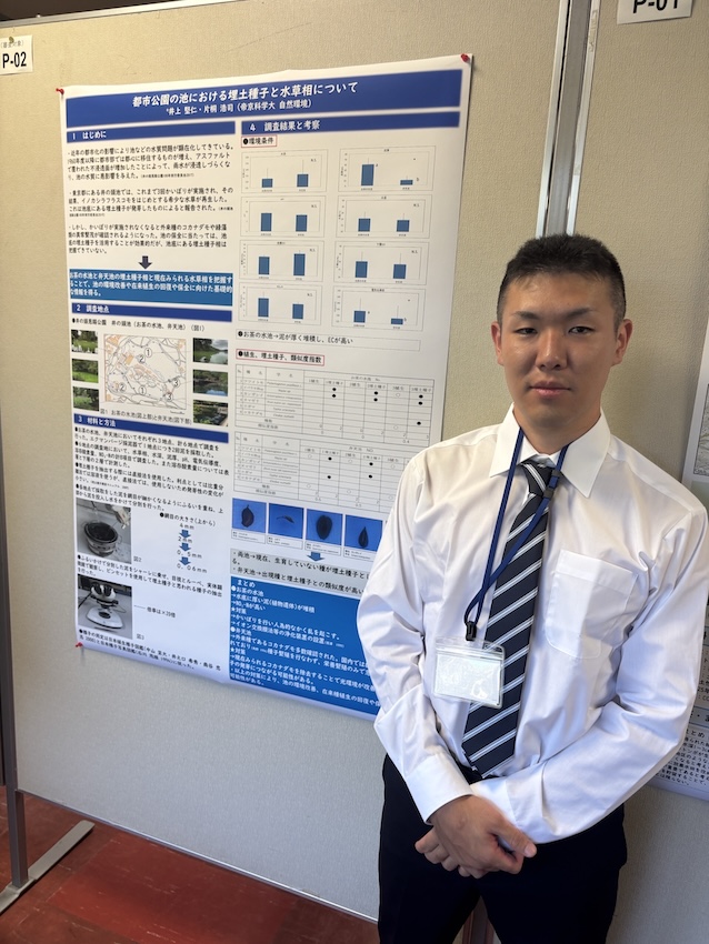ポスター発表の前で緊張している学生